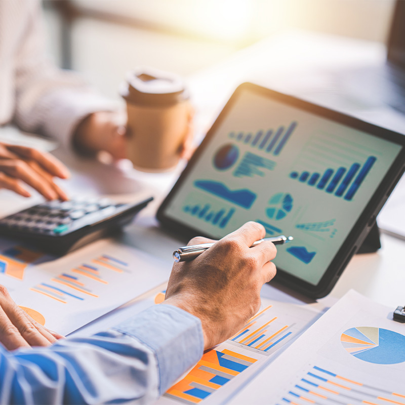 Personas analizando gráficos financieros y de innovación en una tablet y documentos impresos, representando un diagnóstico empresarial basado en datos.
